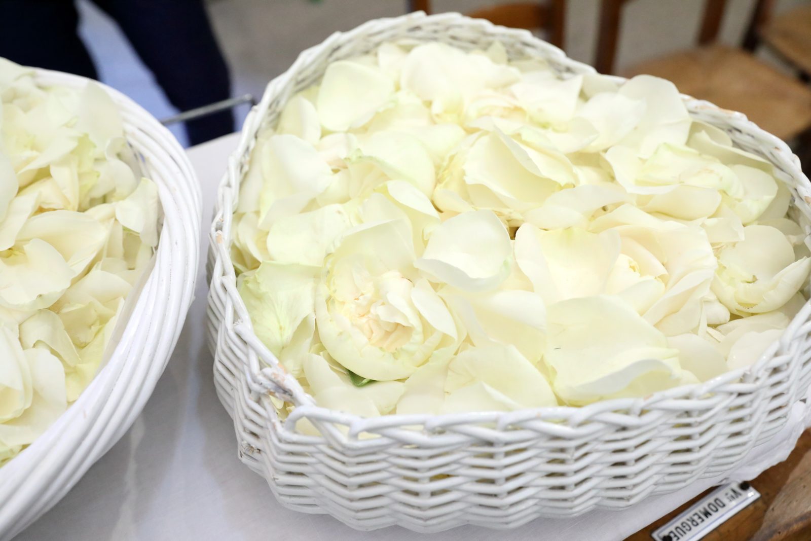 Paniers en osier blanc remplis de pétales de roses blanches, préparés pour la sortie des mariés
