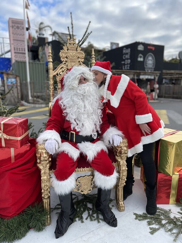 Le Père Noël et la Mère Noël sur le trône doré entre les cadeaux, devant le Marché du Lez