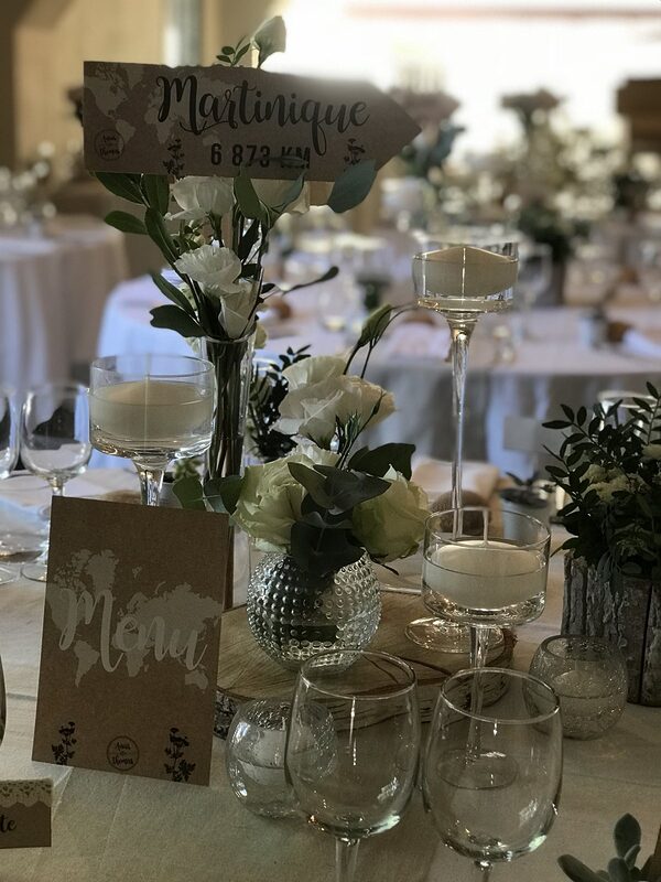 Centre de table : bougies flottantes sur pied, vase boule à picots fleuri sur rondin de bois, photophores en verre craquelé, flèche de destination