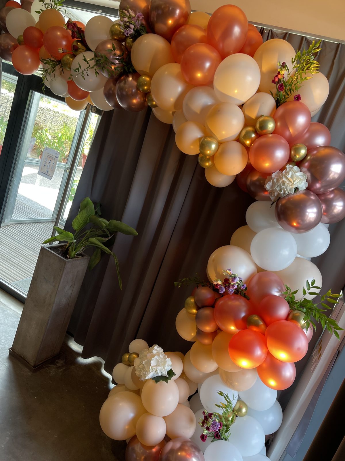 Mur floral rose poudré éclairé derrière une table d’honneur garnie de roses, rondin de bois et bougies
