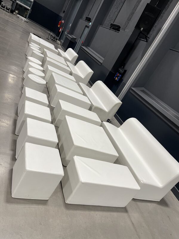 Poufs, banquettes et tables basses blanches du salon lounge en place avant l’installation