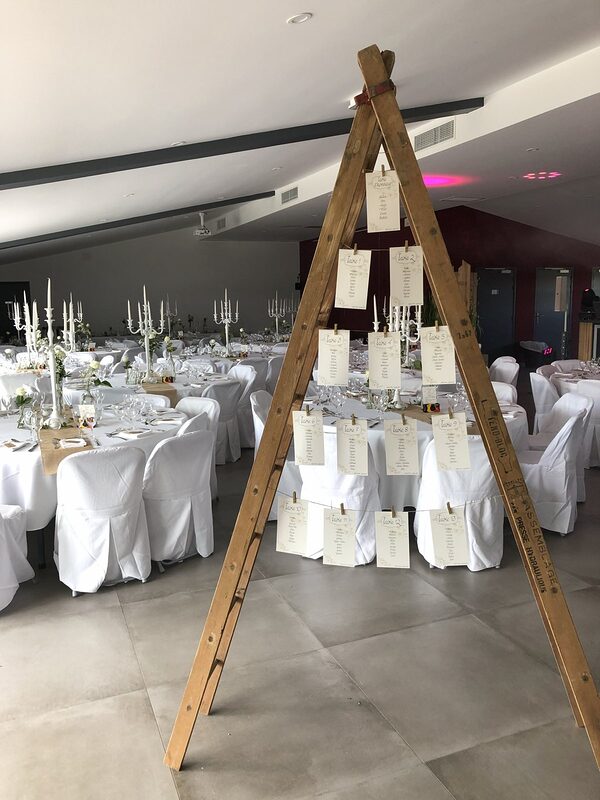 Plan de table suspendu à une échelle en bois, salle aux chandeliers blancs en fond