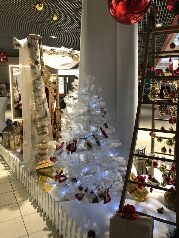 Sapin blanc lumineux orné de petits sacs, tronc de bouleau drapé et échelle en bois garnie de boules rouges et dorées suspendues