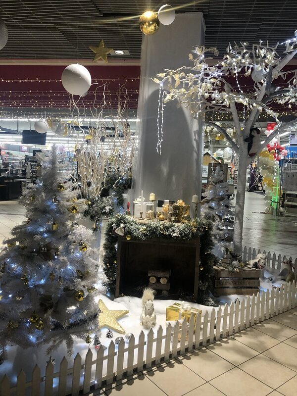 Décor blanc et or : sapin blanc, cheminée en bois habillée de sapin, branches blanches, arbre lumineux, barrière blanche et neige