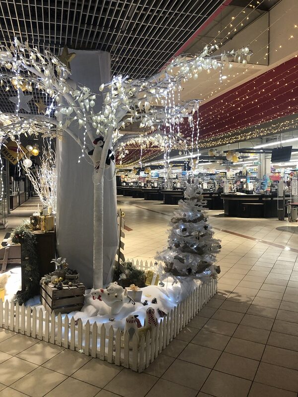 Arbre lumineux blanc au-dessus d’un enclos de neige à barrière blanche, ours polaires, pingouins et sapin blanc devant les caisses