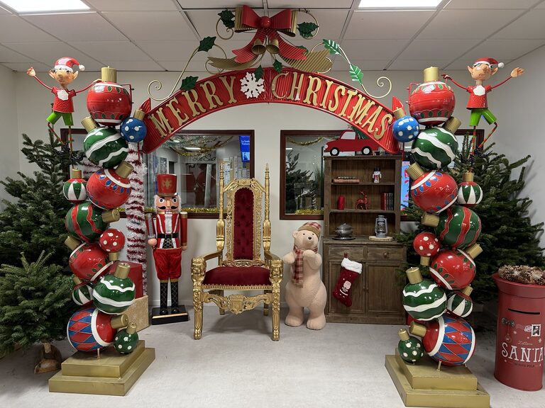 Coin photo de Noël : arche « Merry Christmas » en grosses boules, trône doré en velours rouge, casse-noisette et ours en peluche