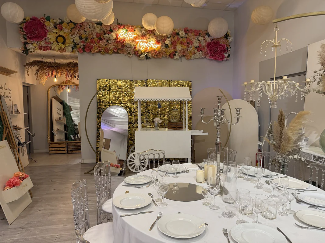 Le showroom Pink Event à Saint-Jean-de-Védas : mur fleuri et néon « Better Together », lampions, charrette candy bar, arches et table ronde dressée aux chaises cristal