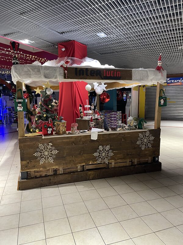 Le chalet des lutins vu de biais dans la galerie, flocons dorés sur le bardage en bois et pilier drapé de rouge